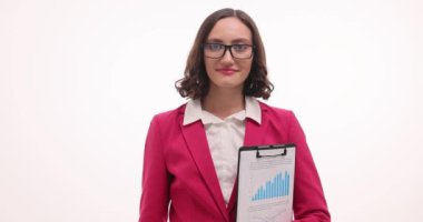 Resmi giyinmiş esmer iş kadını, elinde grafik tutarken iyi niyet göstergesi gösteriyor. Kadın girişimci yavaş çekimde elde edilen başarılardan duyduğu memnuniyeti dile getiriyor
