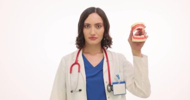 Kadın doktor, çene modelini çikolata çubuğuyla başını sallayarak gösteriyor. Kadın dişçi, şekerin diş sağlığı üzerindeki olumsuz etkilerini yavaş çekimde vurguluyor