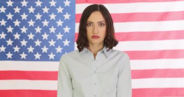 Elleri kelepçeli genç bir kadın marihuana yaprağını Amerikan bayrağına karşı gösteriyor. Esrarın yasallaştırılması ve cezalandırılması kavramı yavaş çekimde ölçülür