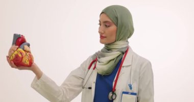 Müslüman kadın doktor, insan kalbi modelini yapıyı göstererek tutuyor. Türbanlı kadın, vücudun ağır çekim ana motoru olarak kalbin önemini vurguladı