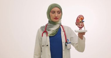 Müslüman kadın doktor konteynır ve böbrek örneğinde idrar örneği tutuyor. Kadın profesyonellerin, üreme organlarının sağlığını yavaş çekimde koruma dürtüleri