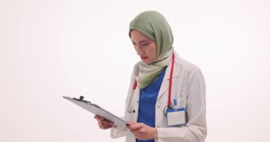 Tesettürlü kadın doktor kâğıtlarla panoya bakar ve neşeyle bağırır. Üniformalı Müslüman kadın, sürpriz ve ağır çekimde mutlu oluyor.