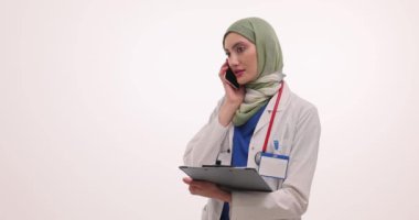 Bayan Müslüman doktor telefonda hastaya muayene sonuçlarını anlatıyor. Hasta tıbbi geçmişi ağır çekimde olan tesettürlü kadın.