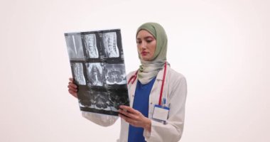 Konsantre kadın doktor tesettüre dikkatlice x-ray görüntülerine bakıyor. Steteskopla çalışan Müslüman çalışanlar bilgisayarlı tomografi üzerinde ayrıntılı çalışmalar yapıyorlar.