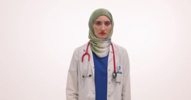 Müslüman kadın doktor başını çevirir ve kollarını kavuşturarak yasağı gösterir. Steteskoplu kadın açık bir protesto ve ağır çekim gösteriyor