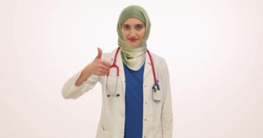 Steteskopla tesettürlü kadın aile doktoru iyi bir jest yapıyor. Üniformalı Müslüman kadın ağır çekimde çalışmaktan zevk aldığını göstermek için ellerini kaldırıyor.