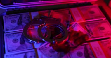 Polis ışıklarının yandığı yerde valizdeki banknotların üzerinde metal kelepçeler var. Yasadışı faaliyetlerin sonuçlarıyla birlikte suç ve yolsuzluğun özü