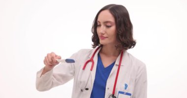 Kadın doktor hamilelik testine bakar ve beyaz arka planda onaylar. Mutlu doktor, pozitif sonuç için yavaş çekim işareti yapar.
