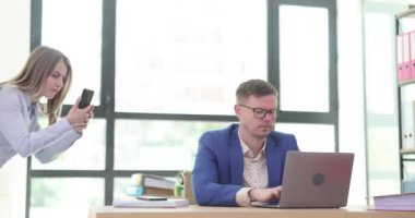 Genç bir kadın bilgisayar ekranındaki iş adamının fotoğraflarını çekiyor. Kadın, ofisteki e-postaların ve özel bilgilerin detaylı fotoğraflarını çekmeye çalışıyor.