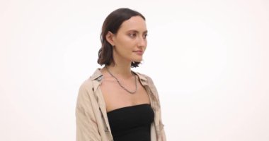 Gülümseyen genç kadın, beyaz arkaplanda konuşurken dikkatle interinterinterlocutor dinler. Esmer kadın günlük kıyafetlerle iletişim kuruyor.
