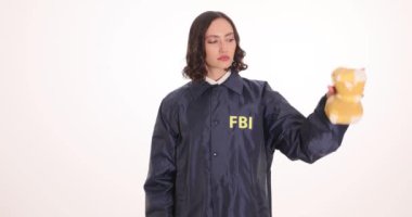 Kadın FBI ajanı beyaz arka planda uyuşturucu paketi ve kelepçe tutuyor. Genç bayan memur ağır suçların cezasını gösteriyor.