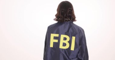 Üniformalı gülümseyen FBI ajanı beyaz arka planda dönüyor. Kadın memur kolluk kuvvetlerinde otorite ve profesyonellik gösteriyor.