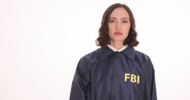 Bayan FBI ajanı beyaz arka planda kelepçeleri kaldırıyor. Üniformalı kadın memur, kolluk kuvvetlerinde profesyonellik gösteriyor.