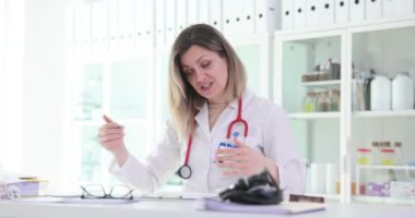 Kadın doktor klinikteki tıbbi kayıtları doldurmak için şarkı söylüyor. Mutlu terapist hastane ofisinde kağıtları kontrol ederken olumlu duygular ifade ediyor.