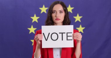 Kadın, AB bayrağına karşı duran oy pusulasıyla kağıt kaldırıyor. Bayan, Avrupa vatandaşlarını demokratik süreçlere katılmaya teşvik ediyor