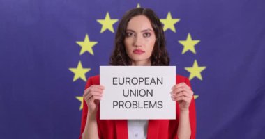 Kadın, AB bayrağı önünde Avrupa Birliği 'nin sorunlarıyla ilgili yazılı bir kağıt tutuyor. Genç bayan Avrupa 'daki ekonomik zorluklar hakkında farkındalığı artırıyor