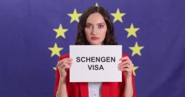 Genç iş kadınının elinde arkasında Avrupa Birliği bayrağı olan SCHENGEN VISA yazılı kartlar var. Avrupa seyahati için belge gerekli