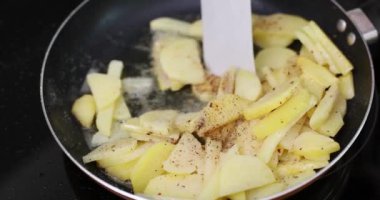 Aşçı dilimlenmiş patatese acı biber ekler tavada kızartılarak spatulayla karıştırılır. Cızırtılı ses yemek pişirme sürecini güçlendirir lezzetli ve lezzetli yemekler yaratır.