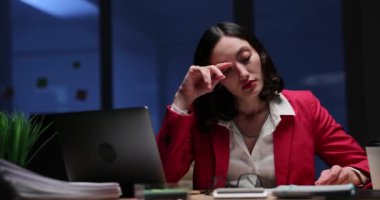 Gece geç saatlere kadar masasında çalışırken çarpıcı kırmızı ceket giymiş bir kadın derin düşünceler içinde belirir.