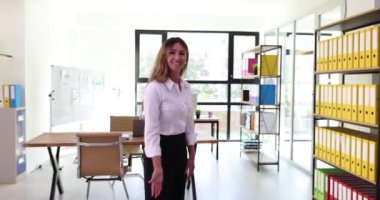 Gülümseyen kadın sekreter modern ofiste ziyaretçiyi selamlıyor. Kibar gülümsemeli profesyonel ofis çalışanı müşteriyi toplantı alanına yönlendiriyor.