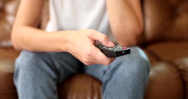 Ev elbiseli bir kadın kanepeye oturur ve uzaktan kumandanın düğmelerine basar. Akşam evde film izliyordum. TV 'de program ara