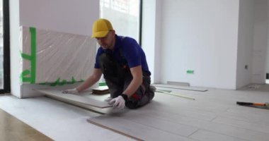 Erkek marangoz eve tahta döşeme döşemesi koyar. Erkek işçi, uzun ömürlü lamine döşeme yenileme işlemini tamamlıyor