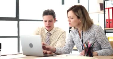 Erkek ve sarışın kadın dizüstü bilgisayarda iş belgelerini inceliyor. Çalışanlar ofis masasında otururken iş dünyasının istatistiksel verilerini inceler