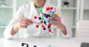 Kadın doktor, hastanede plastik model kullanan moleküllerin yapısını açıklıyor. Laboratuvar önlüklü kadın doktor, derste kimyasal bağlanmayı tanımladı
