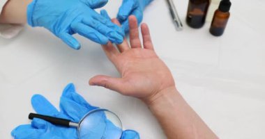 Eldivenli doktor hastane masasında oturan erkek hasta parmaklarına topikal ilaçlar uyguluyor. Üniformalı sıhhiye randevusu sırasında ilaç kullanıyor