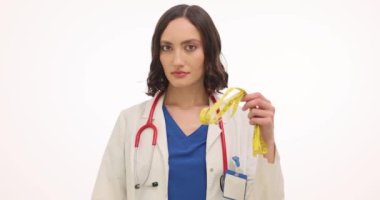 Kadın doktor beyaz arka planda mezura ve çikolata çubuğu kafa sallıyor. Beslenme uzmanı vücut şeklini korumak için tatlı atıştırmalıkları reddediyor.