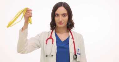 Bayan doktor beyaz arka planda şerit ve soda kadehlerini gösteriyor. Hekim, vücudun iyi durumda olması için tatlı içecekleri yasaklıyor.