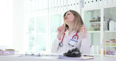 Neşeli kadın doktor kalem taklidi mikrofonda şarkı söylüyor. Laboratuvar önlüklü kadın hekim hastanede çalışırken eğlenceli anlar yaşıyor.