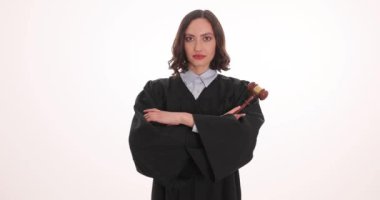 Kendine güvenen kadın yargıç beyaz arka planda tokmak tutarak kollarını kavuşturuyor. Siyah cüppeli esmer avukat gülümseyerek mahkemeye hazırlanıyor.