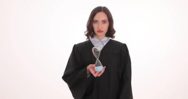 Siyah elbiseli kadın avukat beyaz arka planda kum saatini ters çeviriyor. Ciddi kadın yargıç zaman geçişi kavramını gösteriyor.