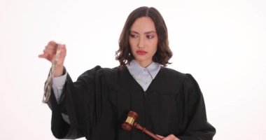 Kadın yargıç, beyaz arka planda tahta tokmak tutan kelepçelerle el kaldırıyor. Kadın, suç eylemlerinin hukuki sorumluluğu konusunda uyardı