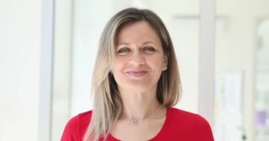 Neşeli sarışın kadın ofiste parmaklarıyla dudaklarını kaldırıyor. Güzel bir kadın gülümsemeyi ve ağır çekimde pozitif enerji yaymayı hatırlatır.