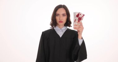 Kadın yargıç, üzerinde kan lekeleri ve kelepçe olan para paketleri gösteriyor. Ciddi kadın mahkeme çalışanları mağdurlarla mali suçları araştırıyor