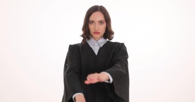 Tokmaklı kadın yargıç beyaz arka plandaki jestleri durdurduğunu gösteriyor. Kadın yargıç hukuki bağlamda hukuki otoriteyi temsil ediyor.
