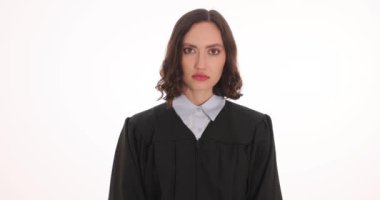 Önlüklü kadın yargıç elleri kelepçeli ve beyaz arka planda tokmak gösteriyor. Mahkemede uzlaşmaz yolsuzluk ve rüşvet ağır çekimde savaşır