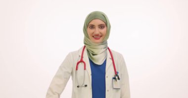 Başörtülü kadın doktor beyaz arka planda iyi niyet göstergesi gösteriyor. Steteskoplu Müslüman kadın terapist destek ve takdirini dile getiriyor