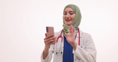 Tesettürlü kadın doktor el kamerasına el sallıyor. Kadın doktor, cep telefonuyla video görüşmesi sırasında selam veriyor.
