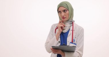 Tesettürlü kadın doktor, tıbbi kayıtların Eureka jestinde parmak kaldırdığını okuyor. Müslüman kadın hasta semptomları için doğru teşhisi buldu
