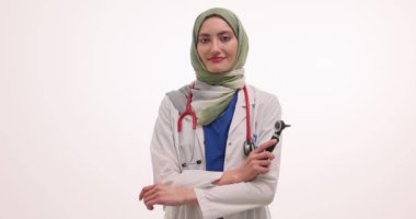 Beyaz arka planda otoskop tutan tesettürlü pozitif kadın doktor. Müslüman tıp uzmanı klinikteki randevusuna hazırlanıyor