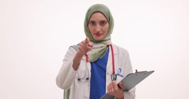 Başörtüsü olan kadın doktor öne doğru işaret ediyor ve beyaz arka planda Call Me hareketi yapıyor. Müslüman kadın teletıp hizmetini yavaş çekimde kullanmayı teklif ediyor