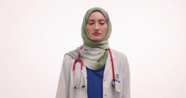 Tesettürlü kadın doktor beyaz arka planda pembe kurdele gösteriyor. Müslüman kadın sıhhiyeci, meme kanserinin düzenli muayeneyi teşvik ettiğini hatırlattı