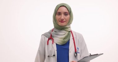 Tesettürlü kadın doktor ultrason sondası ve beyaz pano tutuyor. Müslüman kadın terapist, vücut organlarını makineyle taramaya davet ediyor.