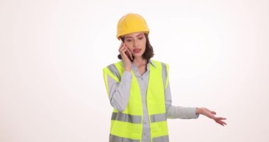 Yansıtıcı yelek giyen kadın mühendis cep telefonunda öfkeyle bağırıyor. Sert şapkalı kadın profesyonel, meslektaşına memnuniyetsizliğini dile getiriyor