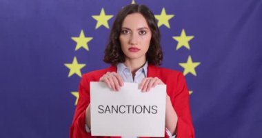 Siyasi lider kadın, AB bayrağına karşı yaptırım uygulayan kağıtları yırtıyor. Kadın, Avrupa 'daki mevcut siyasi krize karşı protesto gösterisi yapıyor