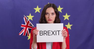 Kadın, Brexit ve İngiliz bayrağının AB amblemine karşı durduğu bir kağıt gösteriyor. Kırmızı ceketli kadın, İngiliz ve Avrupa ekonomisi hakkında endişelerini dile getiriyor