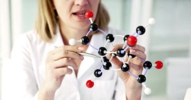 Bir bilim adamı laboratuvar ortamında büyüleyici kimya alanını vurgulayan moleküler bir model sergiliyor.